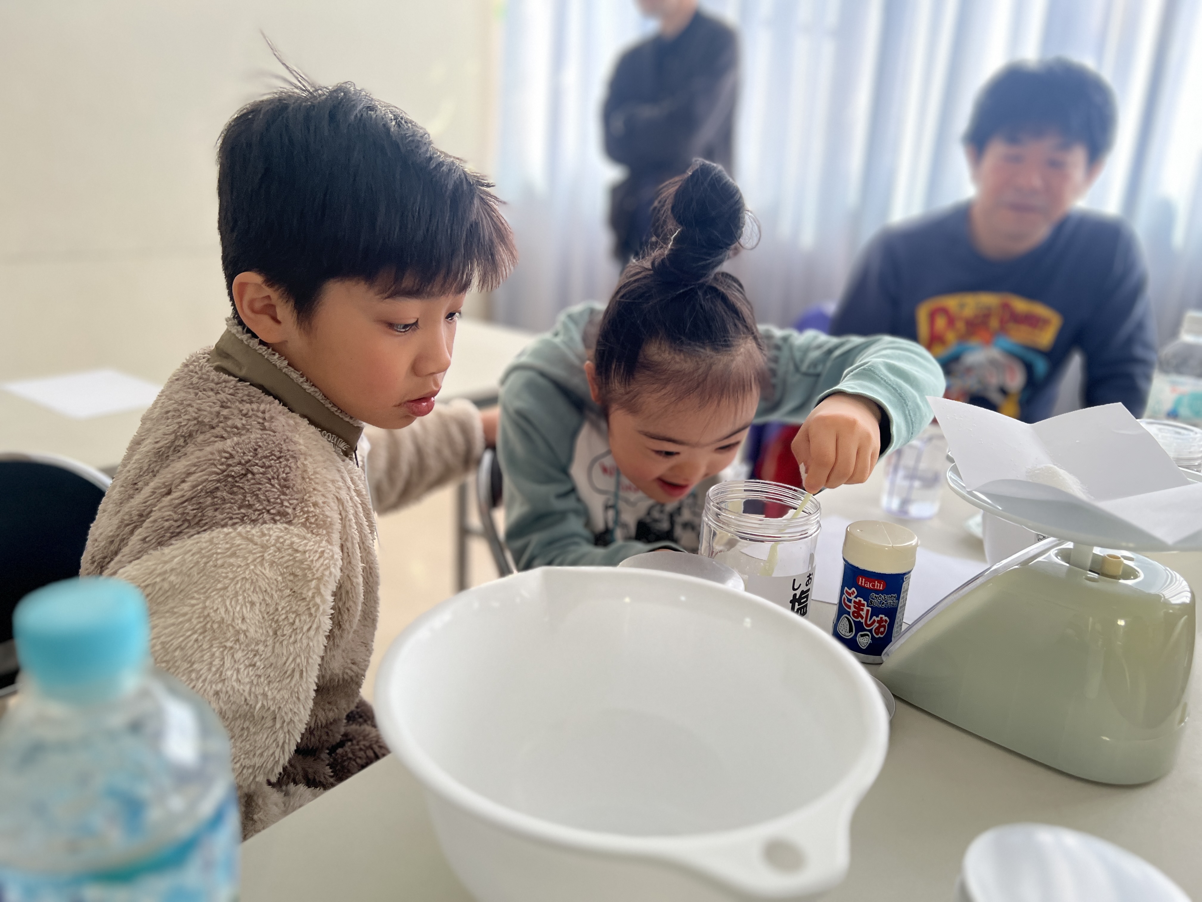 真剣な表情で水に片栗粉を入れて溶けるか確かめる子どもたち